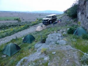 Truck parked on a rocky road with tents, with a mountain view