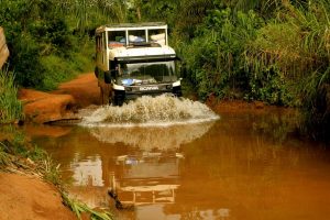 Truck crossing a river splashing up a wall of water in front